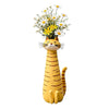 A yellow resin cat figurine with a flower bouquet on its head.