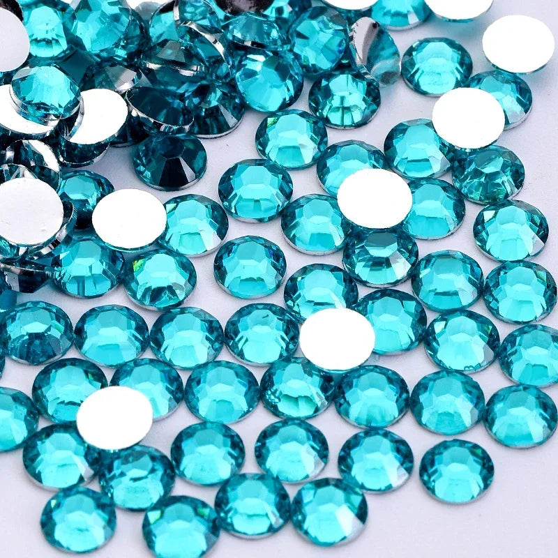 A close-up view of numerous round, flatback resin rhinestones in various shades of turquoise and clear blue.