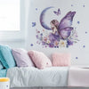 A wall decal featuring a purple crescent moon and a fairy with butterfly wings surrounded by lavender flowers on a white back