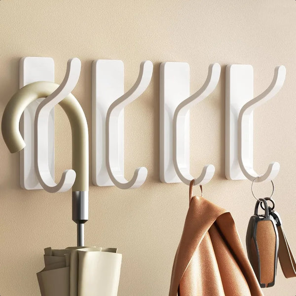 A set of four white self-adhesive wall hooks mounted on a beige wall.