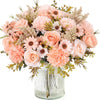 A bouquet of artificial silk roses and daisies in shades of peach, pink, and cream, arranged in a clear glass vase.