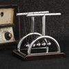 A silver Newton's cradle with balance balls on a dark wooden base.