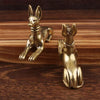 Vintage brass Pharaoh hound statue with upright ears and a collar, displayed on dark wood.