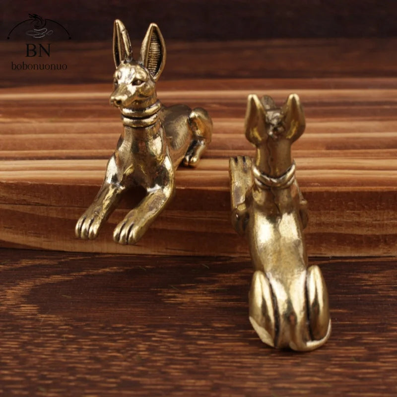 Handmade Egyptian Pharaoh dog statue in gold color resting on a wooden surface.