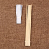 Un éventail main squelette en bambou pliable en bois clair posé sur un tissu brun.