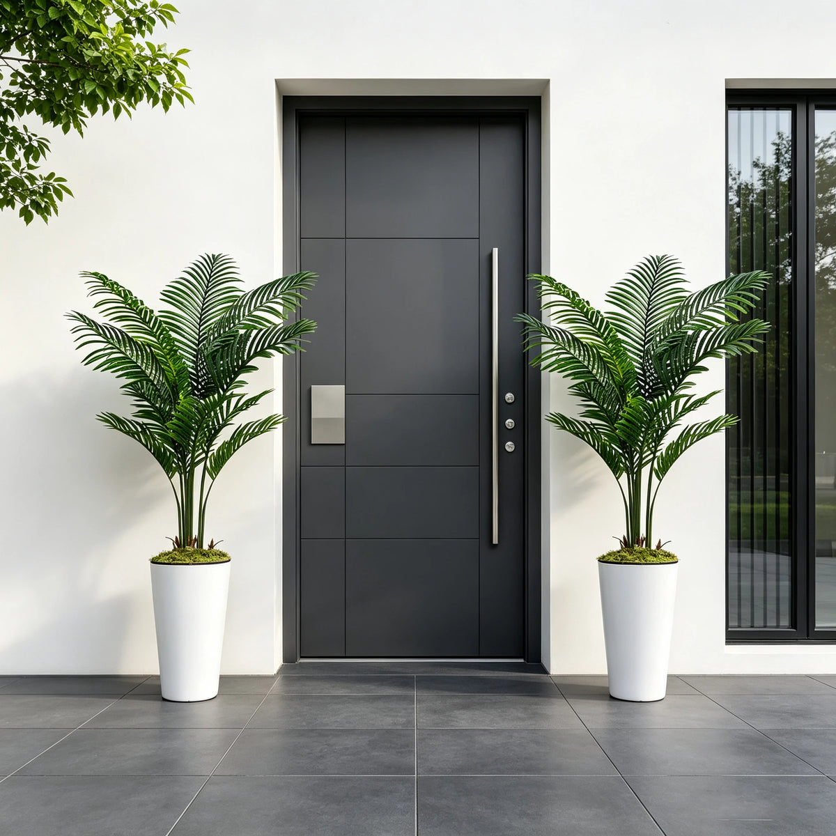 A pair of artificial palm trees in white pots flank a dark gray door on a white wall.