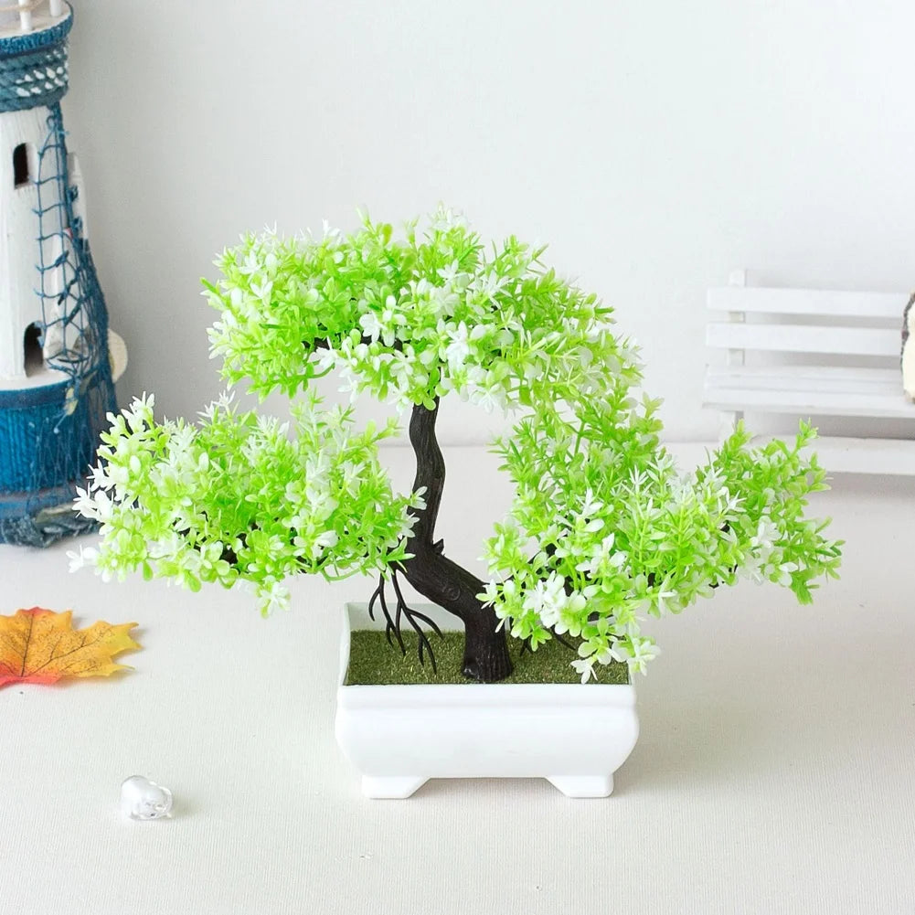 Un petit arbre bonzai artificiel avec du feuillage vert vif et un tronc sombre dans un pot rectangulaire blanc.