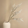 A sprig of artificial silk lover grass with white blossoms displayed in a light colored vase.