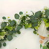 Green artificial eucalyptus leaves and white flowers arranged as a wreath wall hanging garland