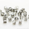 A collection of clear, square cut glass crystal beads for jewelry making scattered on a white surface.
