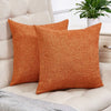 Two solid orange linen pillows resting on a light beige sofa.