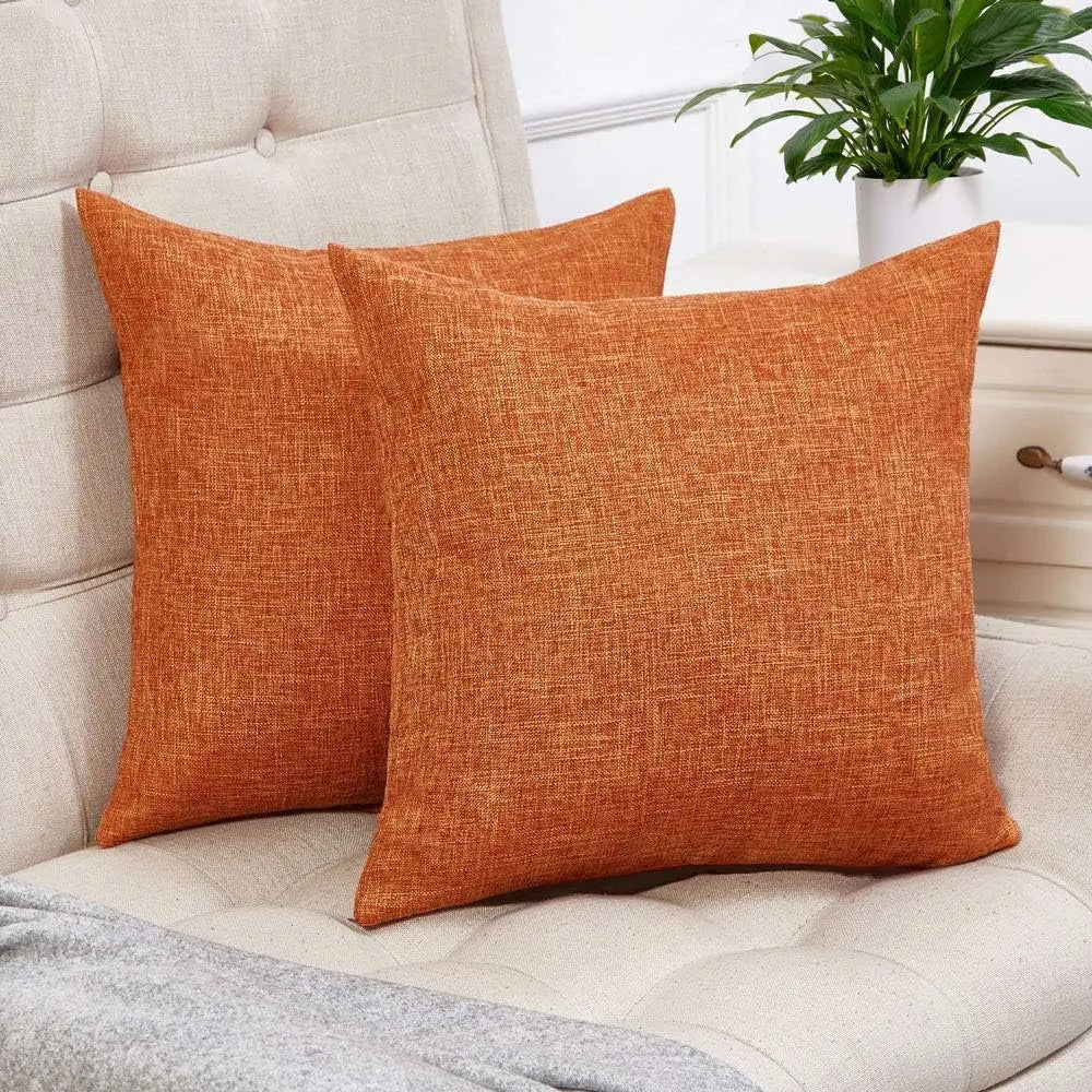 Two solid orange linen pillows resting on a light beige sofa.