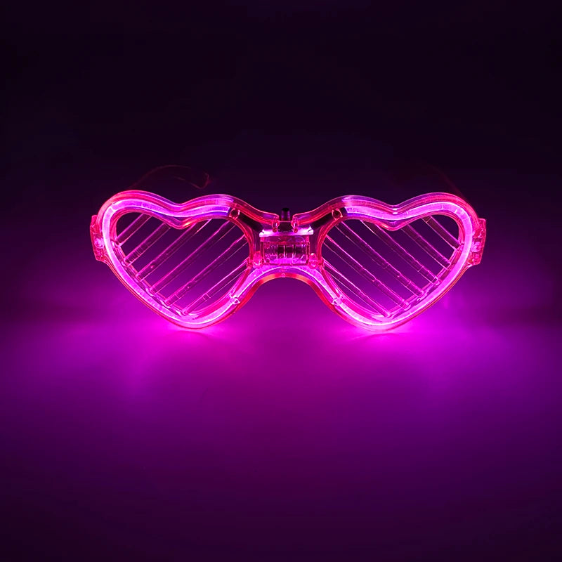 Pink leuchtende herzförmige LED-Partybrille leuchtet hell vor dunklem Hintergrund