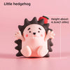 A small, pink hedgehog-shaped cake topper with black spines and a cute face.