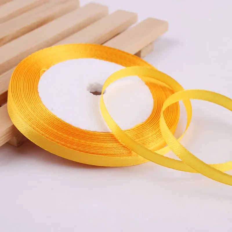 Gold yellow satin ribbon rolled on a wooden stick for crafts and gift wrapping