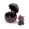 A dark, textured dragon egg is cracked open to reveal a small, dark dragon toy.