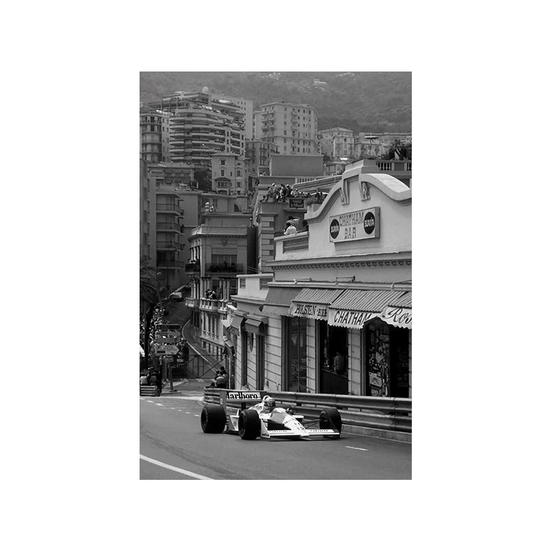 A black and white photo of a vintage Formula Grand Prix racing car driving on a city street.