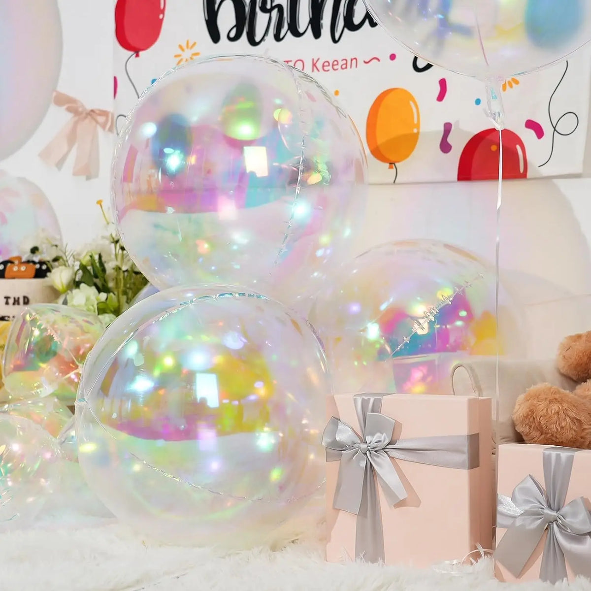 A collection of iridescent holographic round foil balloons in various colors and shades, displayed on a white surface.