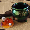 A green ceramic jar with a gold spider design sits on parchment paper next to silicone Halloween pumpkin molds.