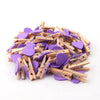 A pile of small wooden photo clips in purple and natural wood colors for crafts and display