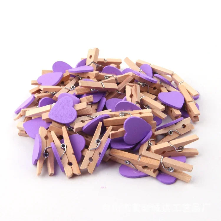A pile of small wooden photo clips in purple and natural wood colors for crafts and display