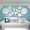 A light blue wall decorated with round acrylic mirror stickers in various sizes and shades
