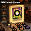 A glowing NFC music player device with 9 discs and a pile of vinyl records in the background.