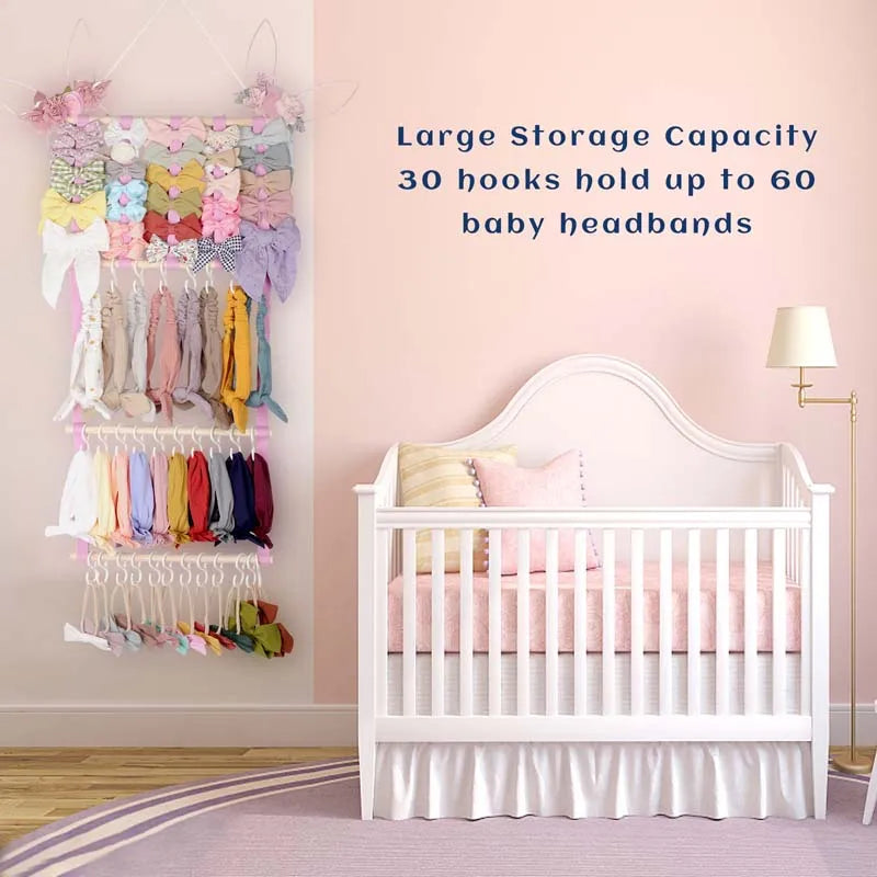A white crib with a pink bedding set and a wall-mounted storage rack for baby headbands.