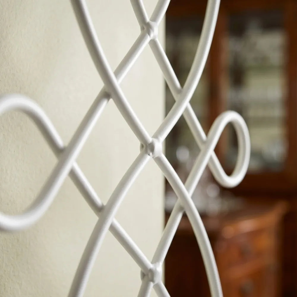Close-up of a white decorative iron wall candle sconce with an ornate scroll design.