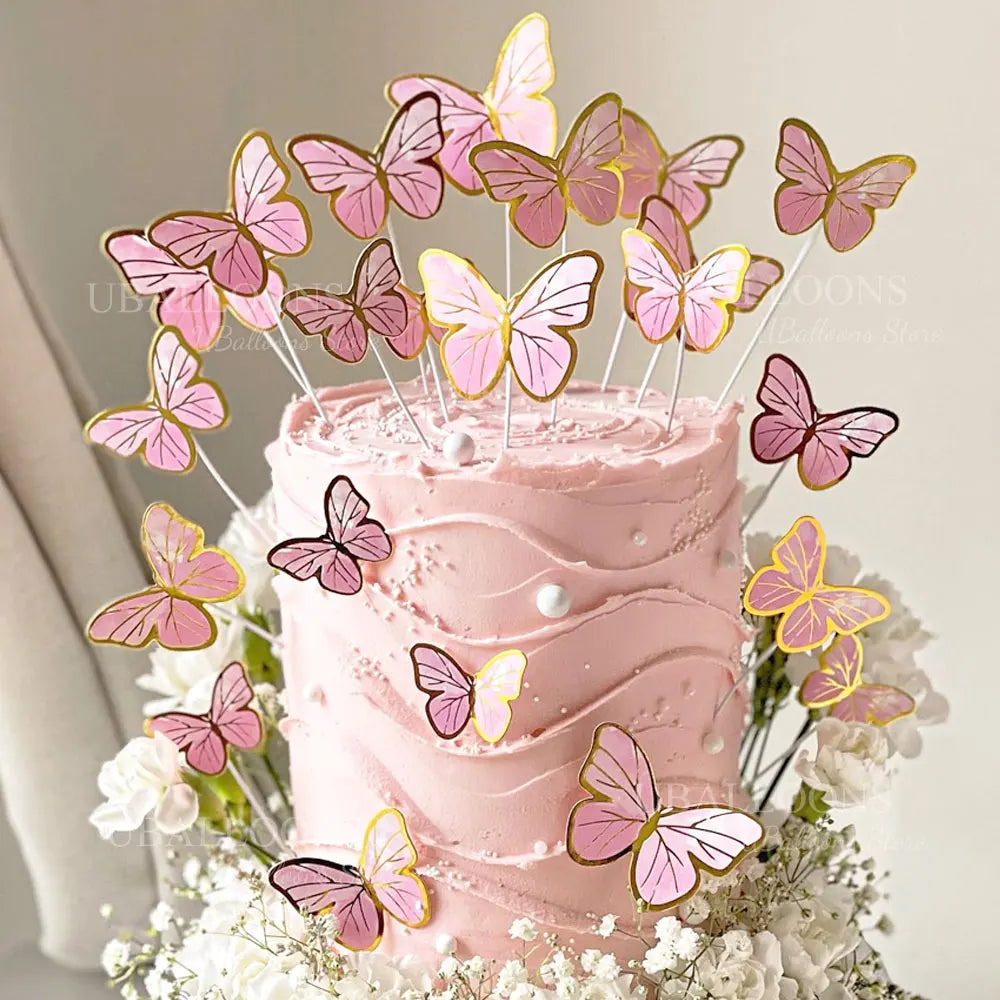 A pink buttercream cake decorated with eleven gold, pink, and purple 3D butterfly toppers.