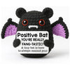 A handmade crochet bat figurine with purple accents and an inspirational card.