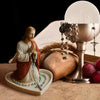 A statue of Jesus with a rosary holder and pearls displayed on a light-colored tray.