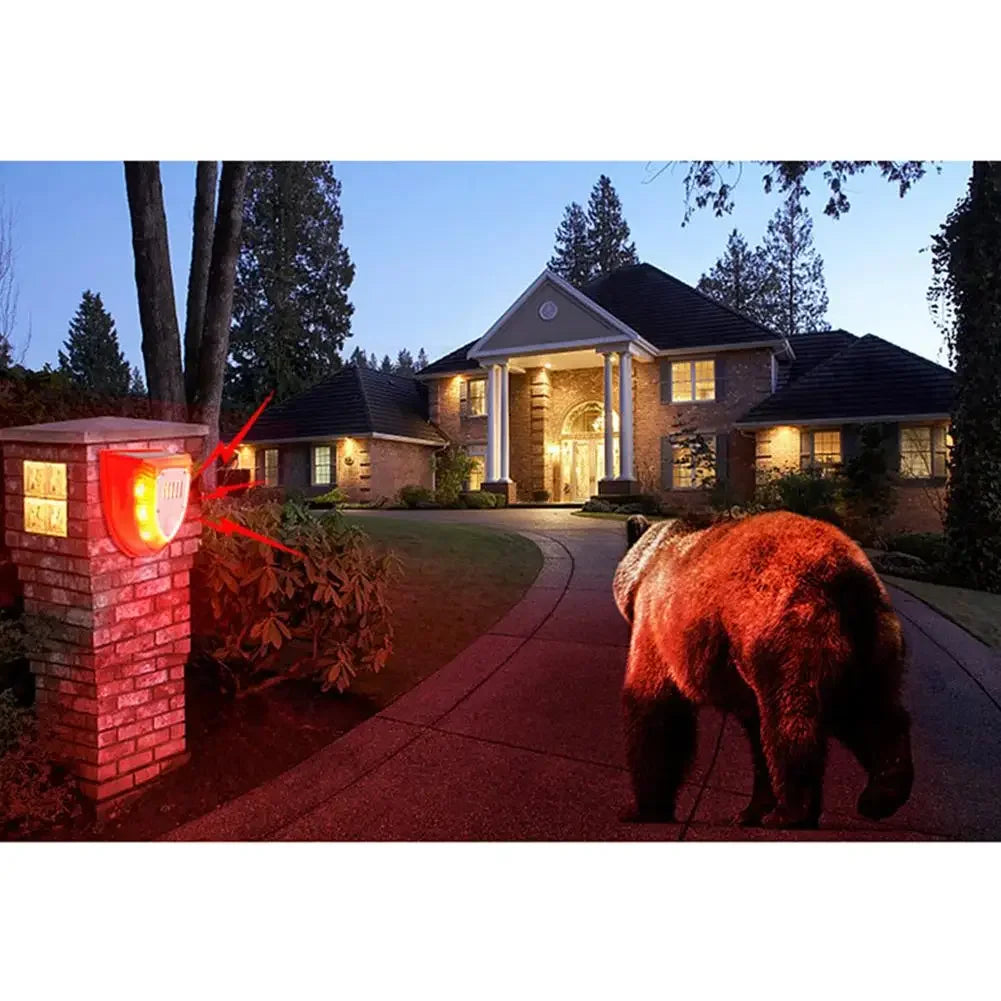 A solar-powered motion sensor alarm with a flashing red siren is installed near a house entrance.