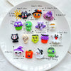 A white plate displays various Halloween resin charms including cats, bats, ghosts, and pumpkins.
