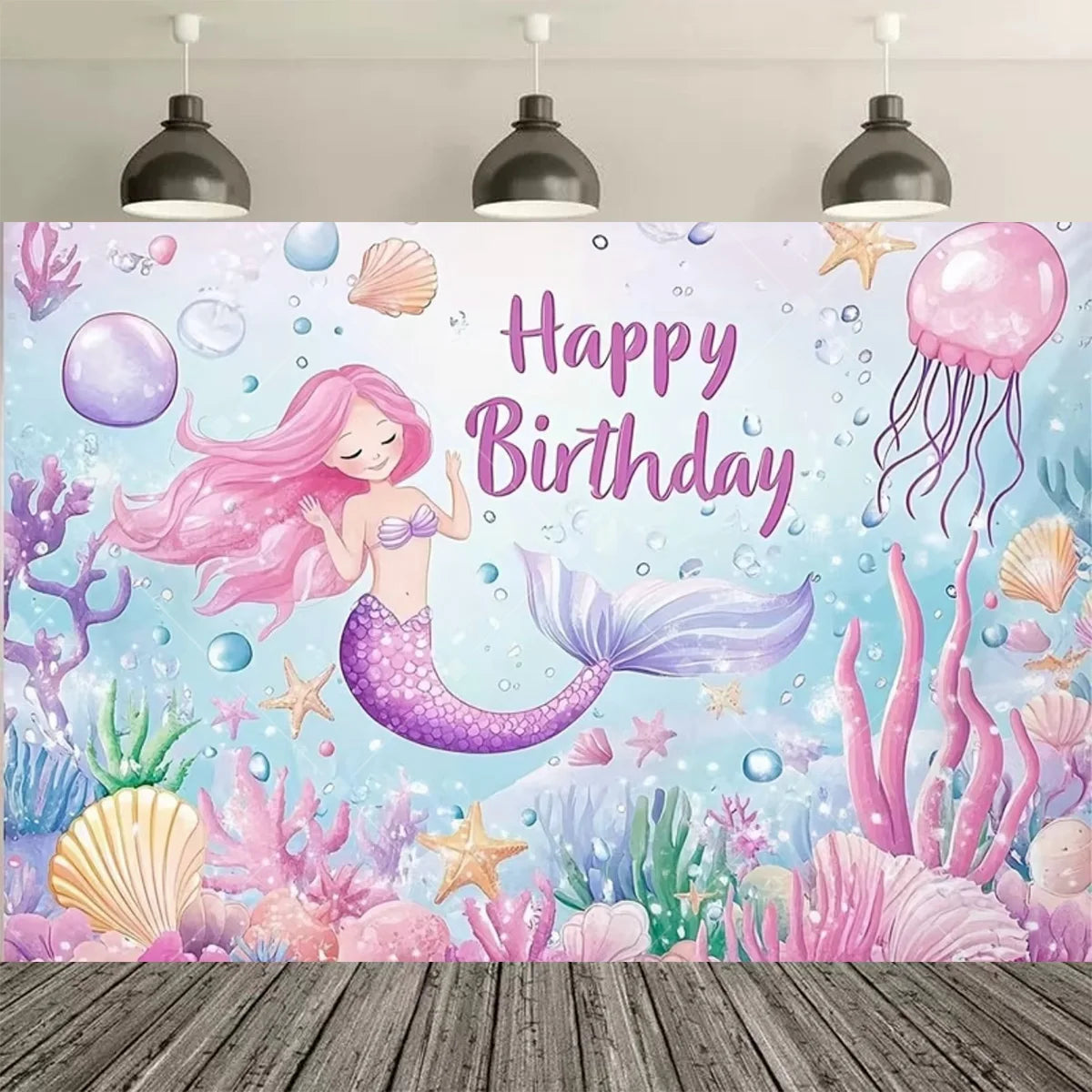 A vibrant mermaid tail birthday backdrop featuring pink and purple scales, sea flora, and bubbles against a blue background.