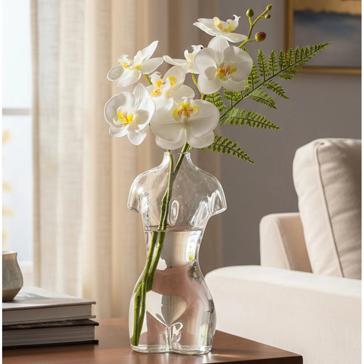 Artistic glass human body vase holding white orchids on a wooden table