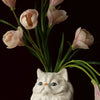 A white ceramic cat sculpture with pink tulips emerging from its form.
