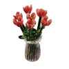 A bouquet of hand-blown glass flowers in shades of pink and red displayed in a clear glass vase.