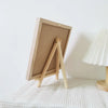A wooden letter message board with a light wood frame and easel stand is displayed on a white surface.
