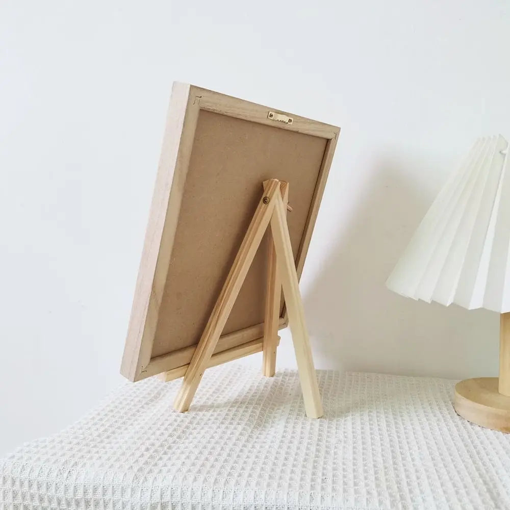 A wooden letter message board with a light wood frame and easel stand is displayed on a white surface.