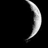 A minimalist black and white print showing a crescent moon against a black background.