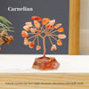 A Carnelian crystal tree featuring natural orange and amber stones mounted on a glass base.