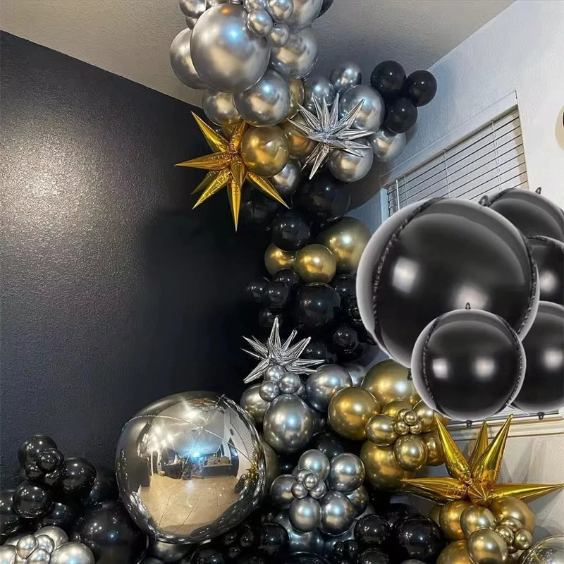 A vertical arrangement of metallic chrome and gold balloons in various sizes and shades against a dark wall.