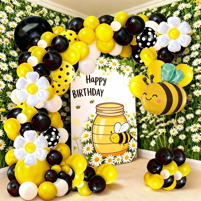 A balloon arch set featuring yellow, black, and white balloons shaped like bees and daisies.