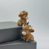A small, brown Highland cow statue with horns is displayed on a dark gray surface.