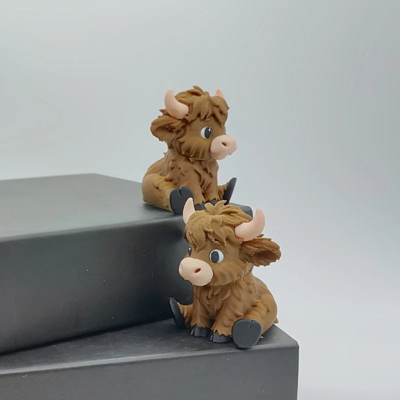 A small, brown Highland cow statue with horns is displayed on a dark gray surface.