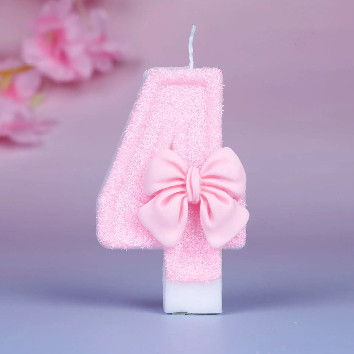 Glittery pink number four birthday candle with a decorative pink bow