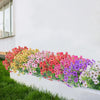 A vibrant bouquet of silk eucalyptus and violet artificial flowers lining a white wall planter.