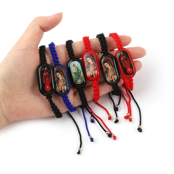 A hand holds several vintage wooden Virgin Mary prayer bracelets in various colors and textures.