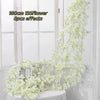 A long white pink sakura flower garland draped against a white wooden background.